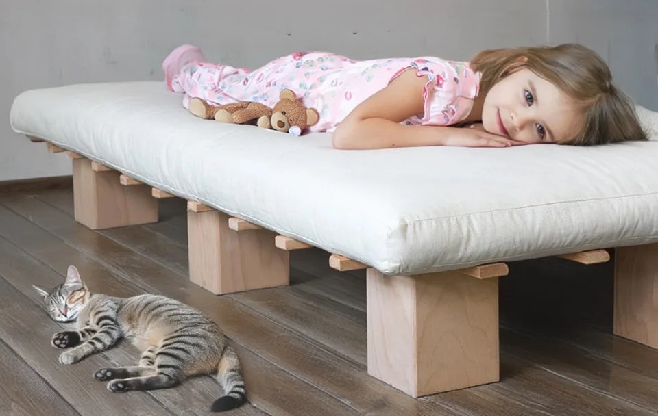 Kind schläft auf Futonmatratze – Katze daneben