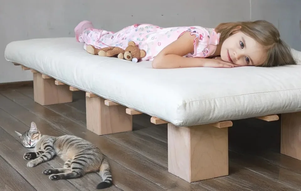 Kind schläft auf Futonmatratze – Katze daneben
